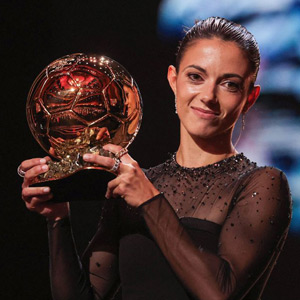 Aitana smiling and holding up trophy while on stage after accepting the balloon d'or for 2023.