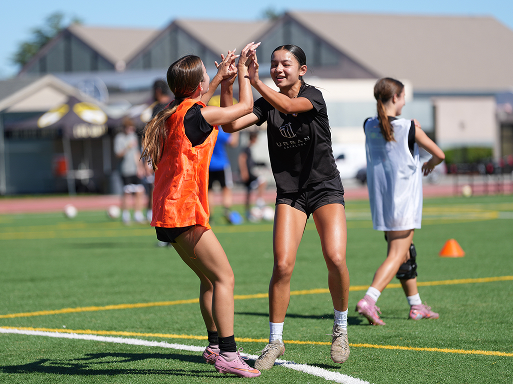 Players sharing a high-five during an LGU summer soccer session in 2026.