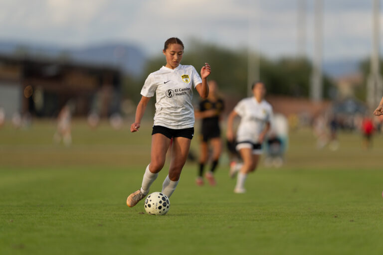 Los Gatos United goalkeeper in pink kit playing the ball