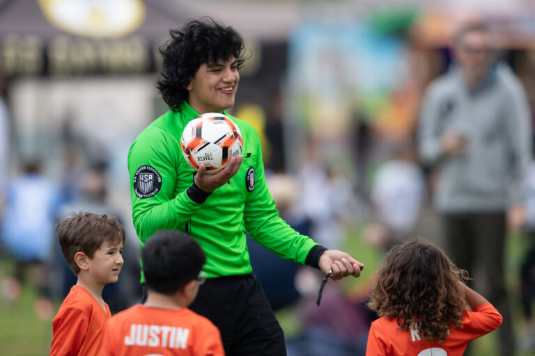 Youth soccer referee smiling while talking with young players