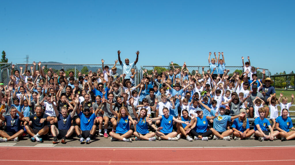 LGU campers and staff gathered on the bleachers with their arms raised.