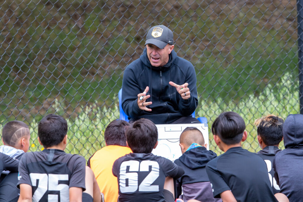 Los Gatos United coach speaking with a group of young players during halftime.