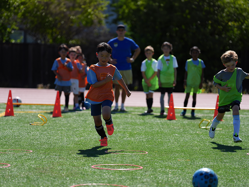 Children practicing with soccer balls and cones during an LGU junior development session in Summer 2026.